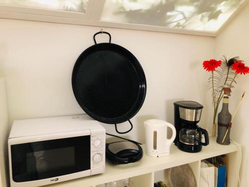a pan hanging above a microwave on a shelf at Albergue la Estacion Santiago de Compostela in Santiago de Compostela
