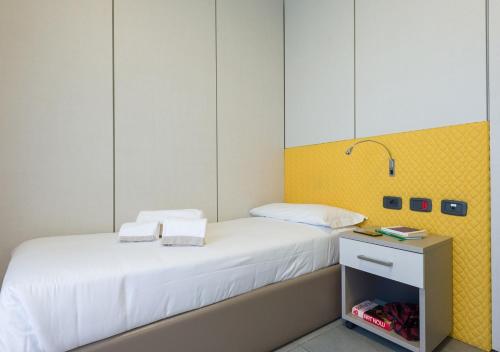 a small bedroom with a white bed and a yellow wall at Camplus Bononia Casa per Ferie in Bologna