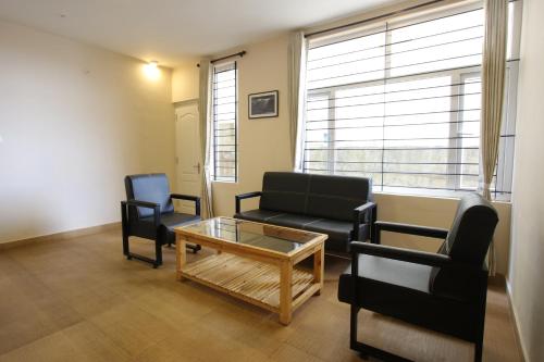 a living room with a couch and chairs and a coffee table at The Hill Side in Ooty