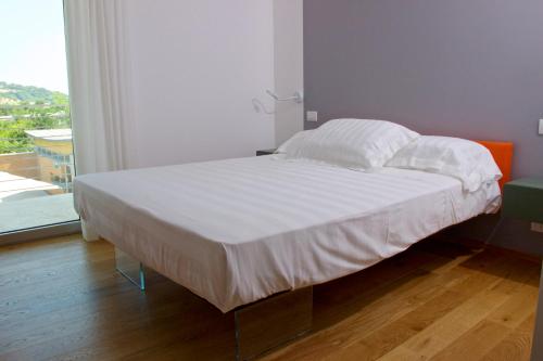 a bed with white sheets and pillows in a bedroom at Chiaroscuro in Belforte del Chienti