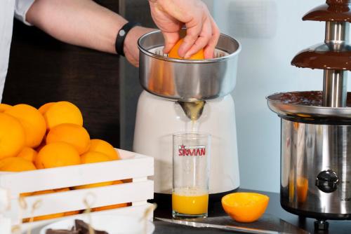 a person is juicing oranges in a blender at Hotel Nazionale in Matera