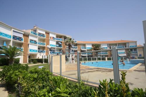 un grand immeuble avec une piscine en face de celui-ci dans l'établissement Résidence la Voile Blanche 3, à Frontignan