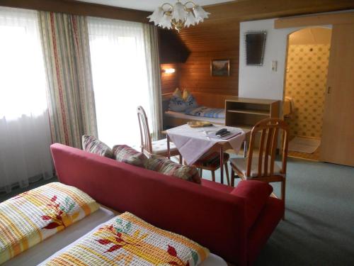 a living room with a red couch and a table at Haus zur Linde in Wagrain