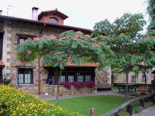 una casa de piedra con un árbol delante en Agroturismo Iturbe en Axpe de Busturia