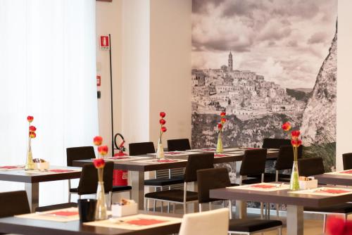 a room with tables and chairs with a painting on the wall at Hotel Nazionale in Matera