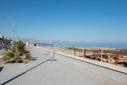 a beach with people walking down a sidewalk at Sunny Beach Apartments in Rethymno Town