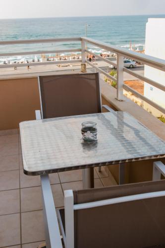 a table on a balcony with a view of the beach at Sunny Beach Apartments in Rethymno Town