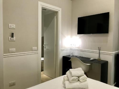 a room with a table and a television and towels at KUKKA ROOMS in Naples
