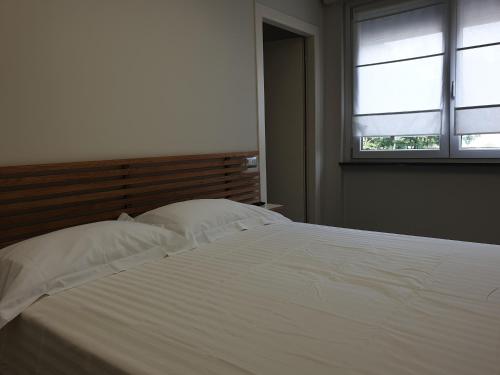 un letto bianco in una camera da letto con finestra di Residence Campo Rotondo a Tavernerio