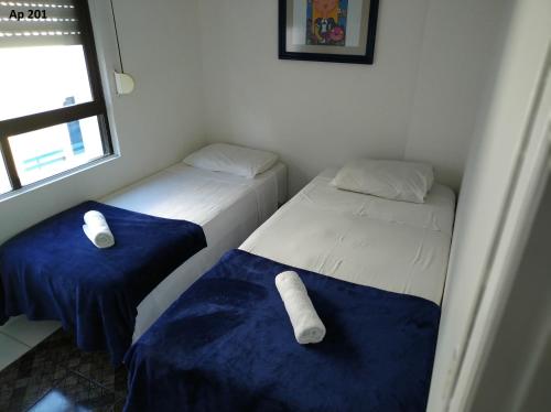 two beds in a room with blue and white sheets at Goldani Lexus Plaza in Florianópolis