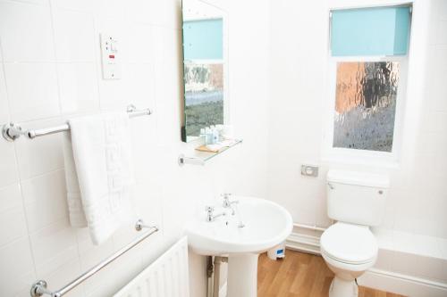 La salle de bains blanche est pourvue d'un lavabo et de toilettes. dans l'établissement Crown Inn, à Marston Montgomery