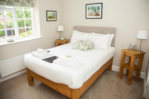 a bedroom with a bed with white sheets and two windows at Crown Inn in Marston Montgomery