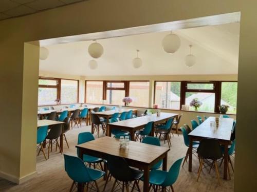 a dining room with tables and chairs and windows at FSC Slapton Ley Hostel in Kingsbridge