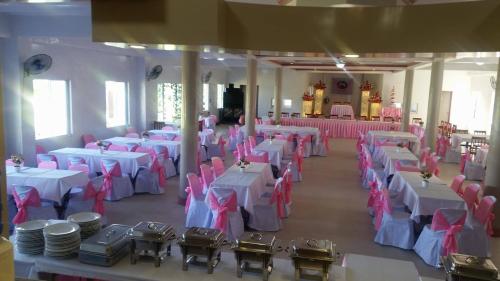 un salón de banquetes con mesas blancas y sillas rosas en Calicoan Villa, en Sarog