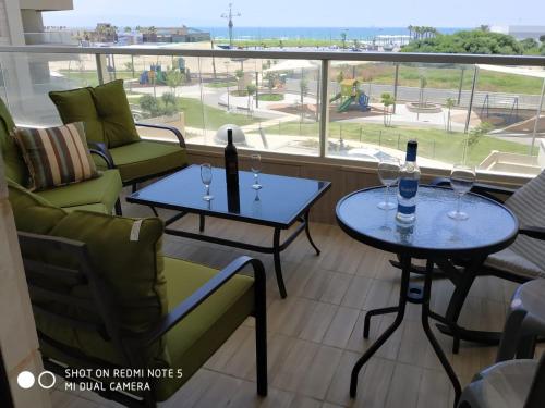 a balcony with two tables and chairs and a view of the ocean at עכו דירה חדשה ליד הים- Akko-brand new apartment in Acre