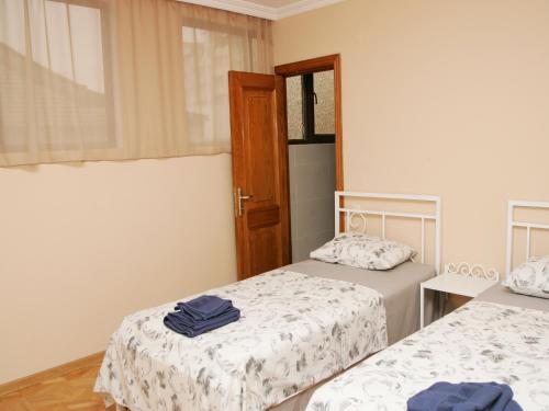 a room with two beds and a window and a door at Two Towers Guest House in Kutaisi