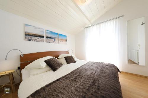 a white bedroom with a large bed with two pillows at Apartment Josip in Vir