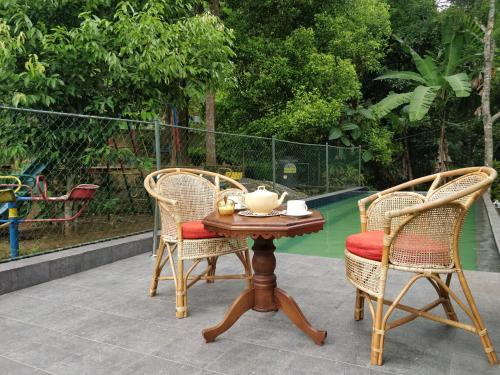 two chairs and a table with a tea pot on it at Alfred Colonial Bungalow & Spice Garden in Kobbekaduwa