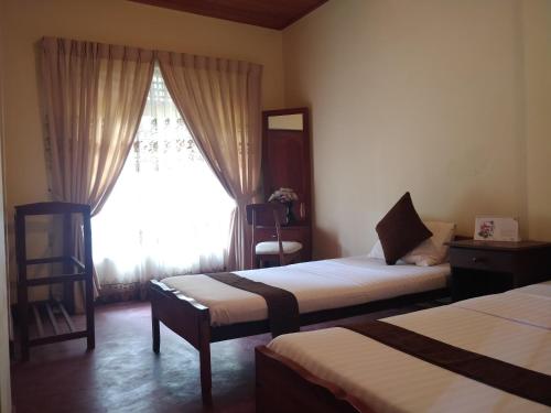 Habitación de hotel con 2 camas y ventana en Alfred Colonial Bungalow & Spice Garden en Kobbekaduwa