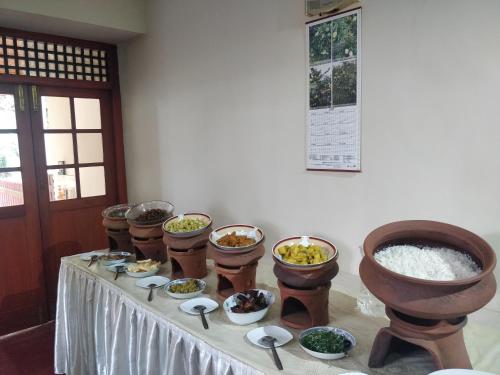 a table with bowls of food on top of it at Alfred Colonial Bungalow & Spice Garden in Kobbekaduwa