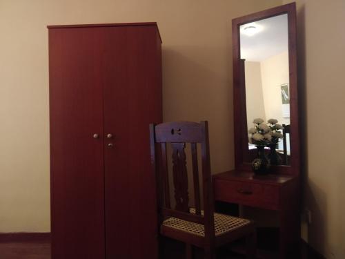 a red cabinet next to a mirror and a chair at Alfred Colonial Bungalow & Spice Garden in Kobbekaduwa
