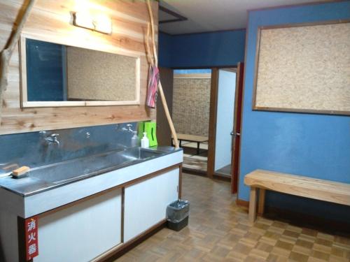 a kitchen with a sink and a table and a bench at 伊豆 白浜 ゲストハウス茉心 in Shimoda