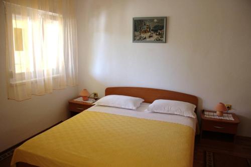 1 dormitorio con 1 cama y 2 mesitas de noche con ventana en Apartments Nadica - free parking, en Nin