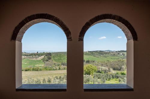 two arched windows in a building looking out at a field at Agriturismo Casale Ugolini in Montespertoli