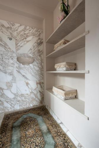 a bathroom with white marble walls and shelves at Agriturismo Casale Ugolini in Montespertoli