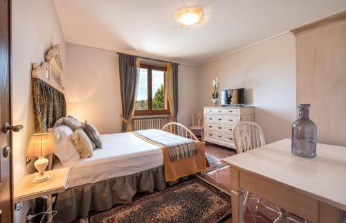 a bedroom with a bed and a desk and a window at Agriturismo Casale Ugolini in Montespertoli