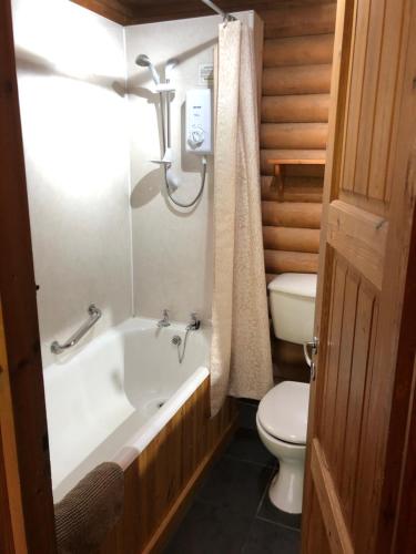 a bathroom with a white tub and a toilet at Highgarry Lodges in Invergarry