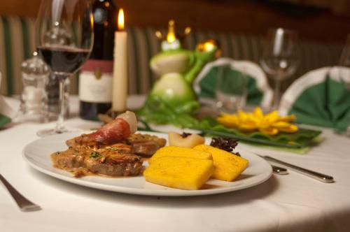 a plate of food on a table with wine glasses at Gartenresidence Stephanie by Hotel Rotwand in Laives