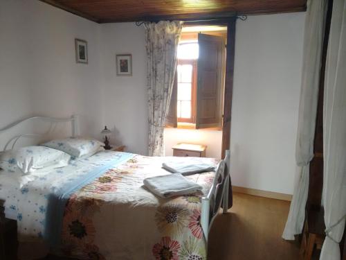 Schlafzimmer mit einem Bett und einem Fenster in der Unterkunft Casa de Alagoa in Arganil