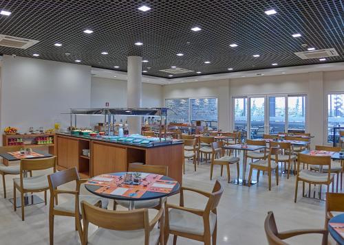 a dining room with tables and chairs and windows at Rio Hotel by Bourbon Campinas in Campinas