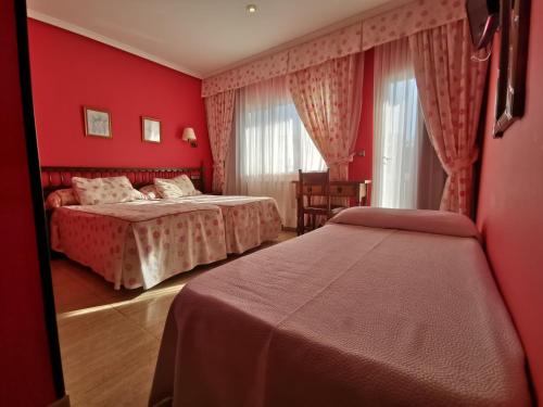 1 dormitorio rojo con 2 camas y ventana en Hotel Pipo, en A Lanzada