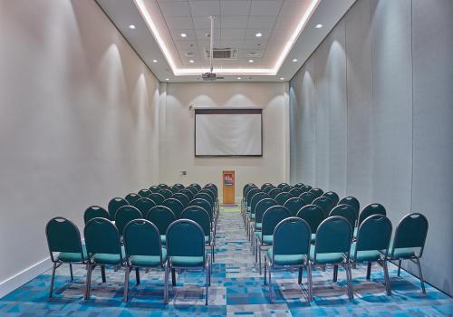 a conference room with chairs and a screen at Rio Hotel by Bourbon Campinas in Campinas