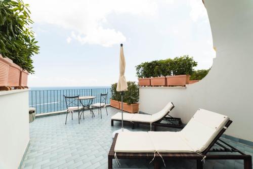 a balcony with chairs and a table and the ocean at Hotel Il Nido in Amalfi