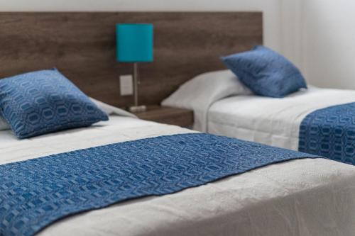 2 łóżka z niebieskimi poduszkami w pokoju w obiekcie JUUB @ THE SOUL OF OAXACA (R3) w mieście Oaxaca
