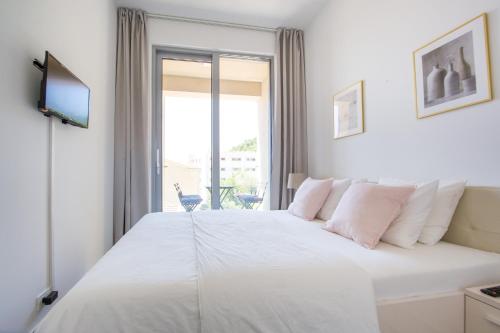 een slaapkamer met een groot wit bed en een raam bij Apart SKY Residence with sea view in DELMAR in Budva