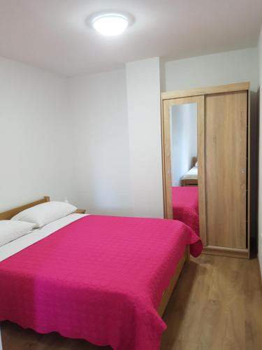 Un dormitorio con una cama con una manta rosa. en Apartmani Benjamin, en Bibinje