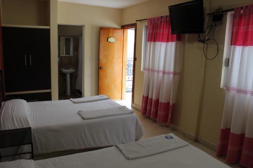 a hotel room with two beds and a television at Hotel Casablanca Tuxtla in Tuxtla Gutiérrez