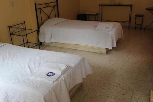 two beds in a room with white sheets and towels at Hotel Casablanca Tuxtla in Tuxtla Gutiérrez