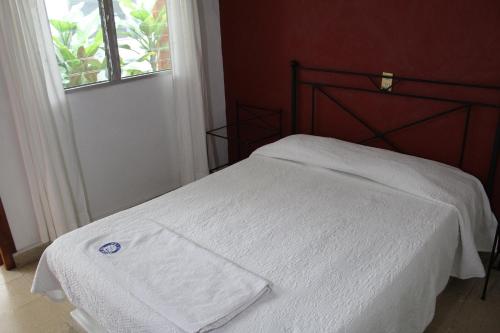 a bedroom with a bed with white sheets and a window at Hotel Casablanca Tuxtla in Tuxtla Gutiérrez