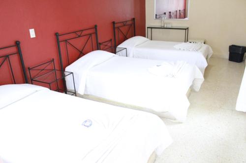 three white beds in a room with red walls at Hotel Casablanca Tuxtla in Tuxtla Gutiérrez