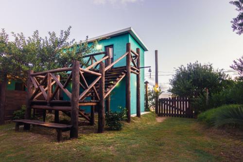 a green house with a bench in front of it at La Brújula Hostel in La Paloma