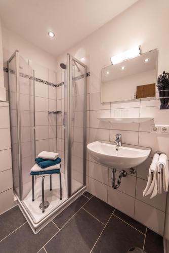 a white bathroom with a sink and a shower at Gästehaus Alpenflora in Fischen