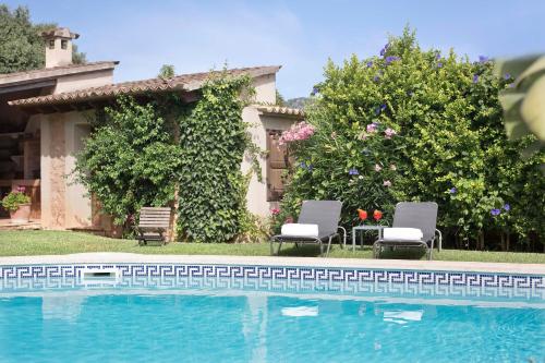 a swimming pool with two chairs and a house at Finca Ca'n Quatre in Sóller