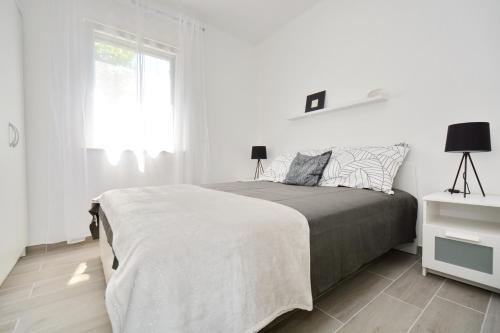 a white bedroom with a bed and a window at Apartments Piazza in Nin