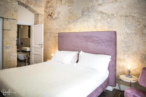 1 dormitorio con 1 cama grande y pared morada en Arcipelago 37, en Cagliari