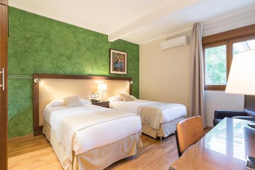 two beds in a hotel room with green walls at California in Málaga